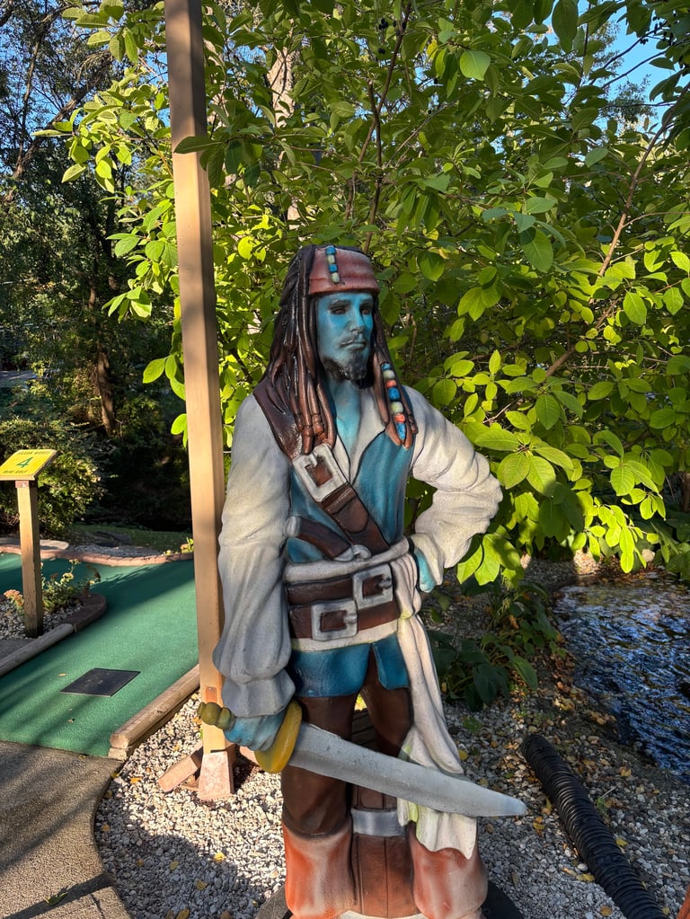 Pirate character statue at miniature golf course surrounded by green foliage